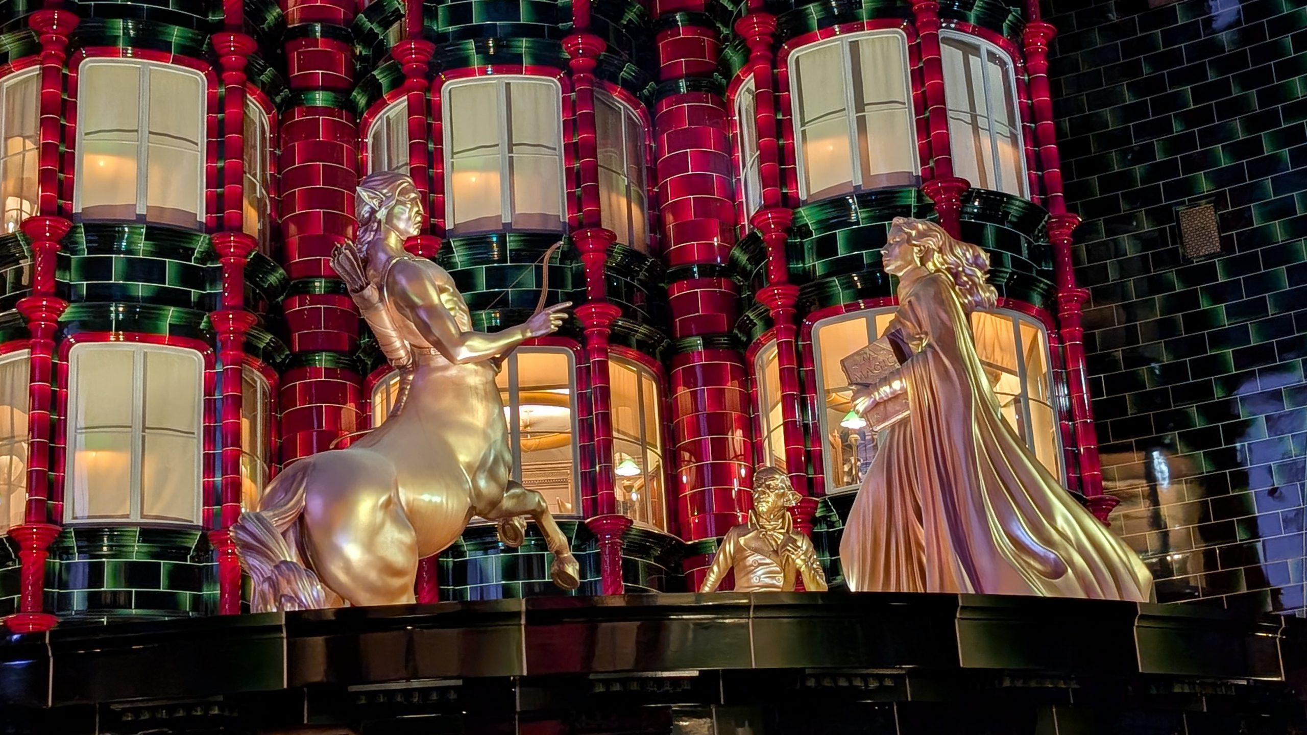 Golden statues on the tiled facade of the Ministry of Magic in the evening